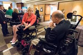 Woman in wheelchair talking to a man in a wheelchair 
